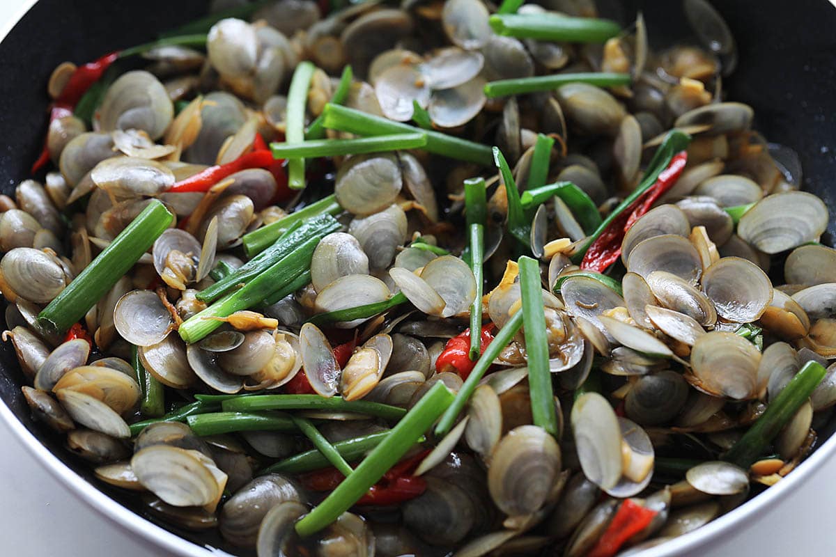 Adding scallions to the stir fried lala clams. 