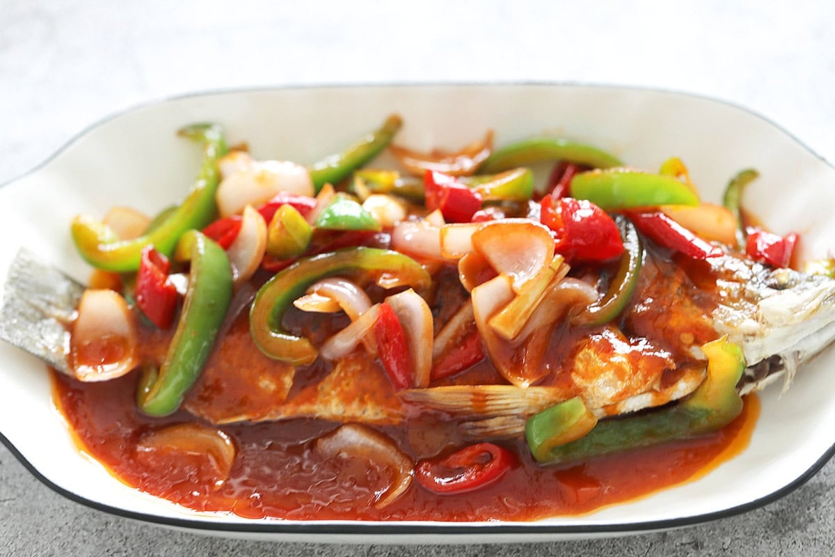 Sweet and sour fish topped with sweet and sour sauce on a plate.