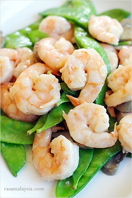 Stir fry shrimps with snow peas and brown Asian sauce.