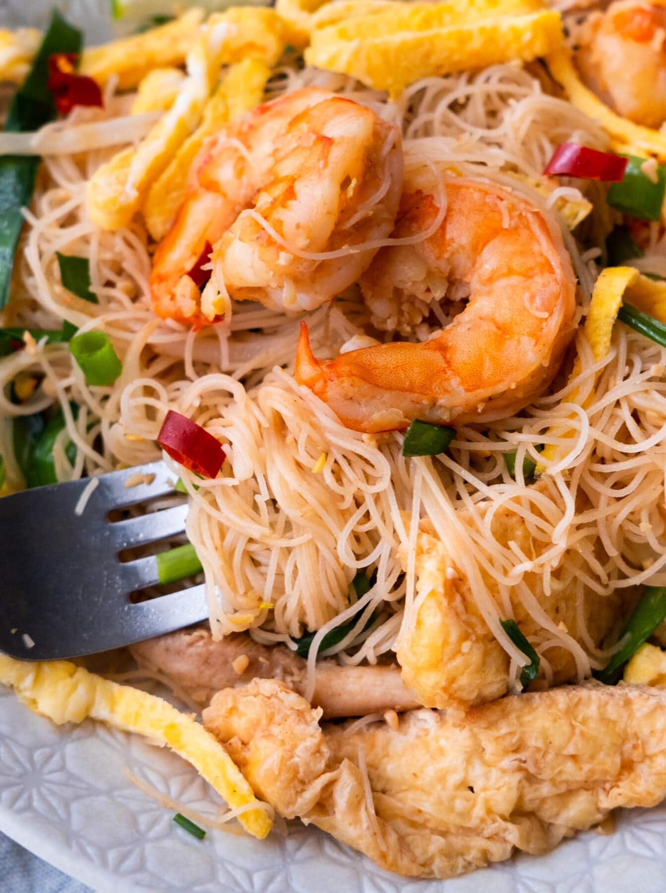 Spicy fried rice vermicelli noodles on a fork. 