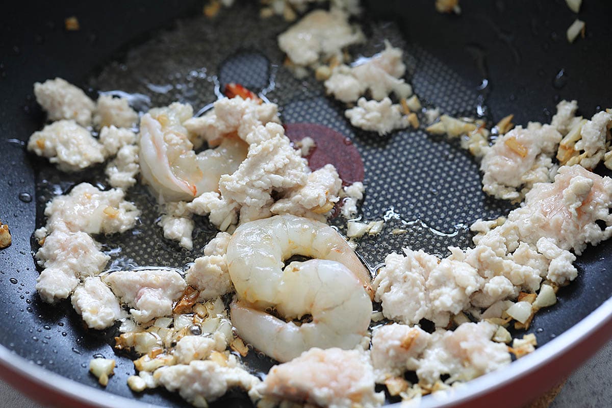 Garlic, shrimp and ground chicken in a wok.