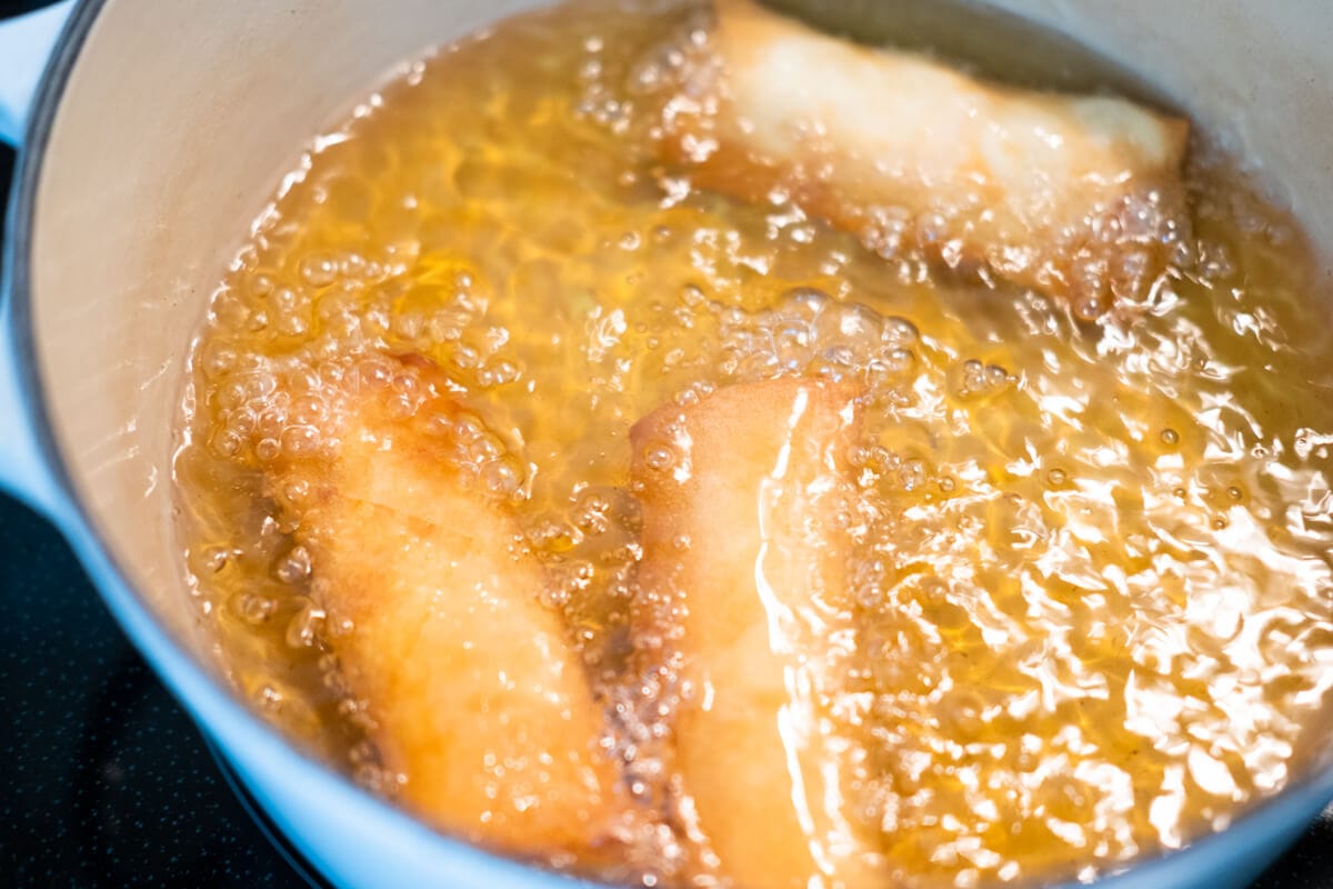 Deep fry the spring rolls in a pot until golden brown and crispy. 