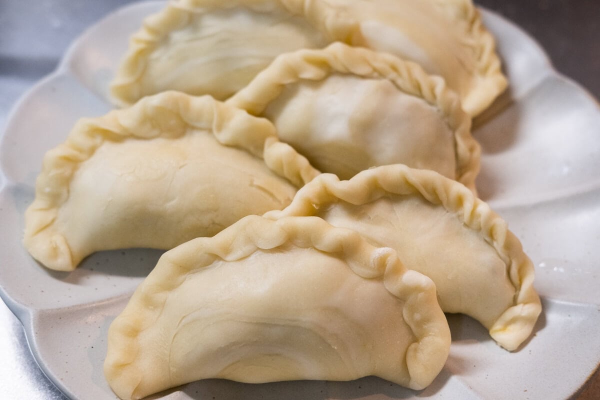 Curry puffs on a plate, ready for deep frying. 