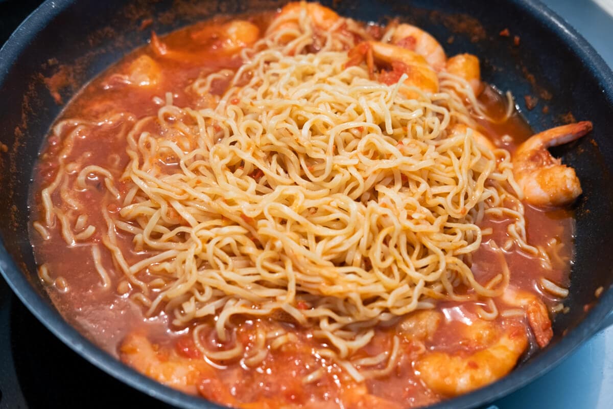 Cook the prawn with tomato puree, tomato sauce, chili paste and yellow noodle in the pan. 