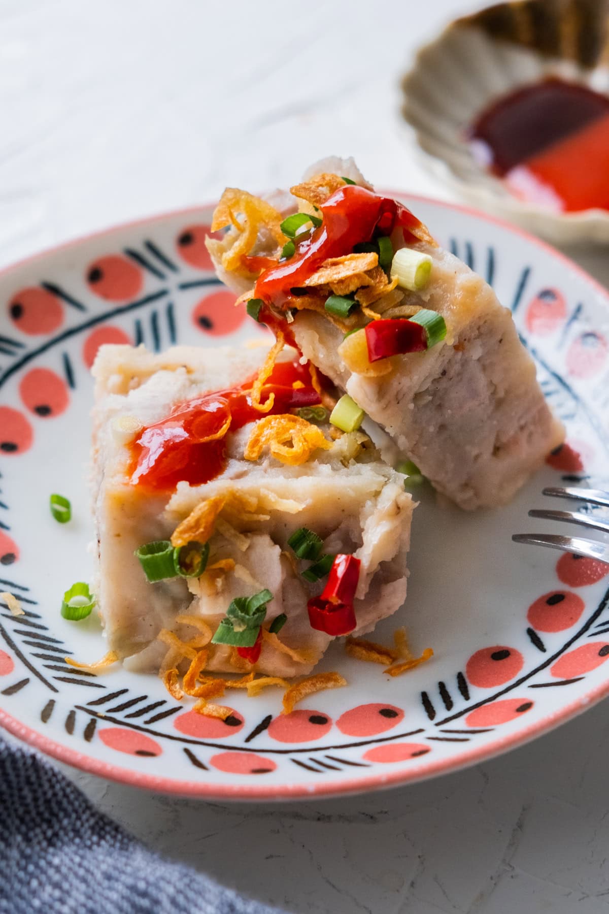 Two slices of yam cake topped with chili sauce. 