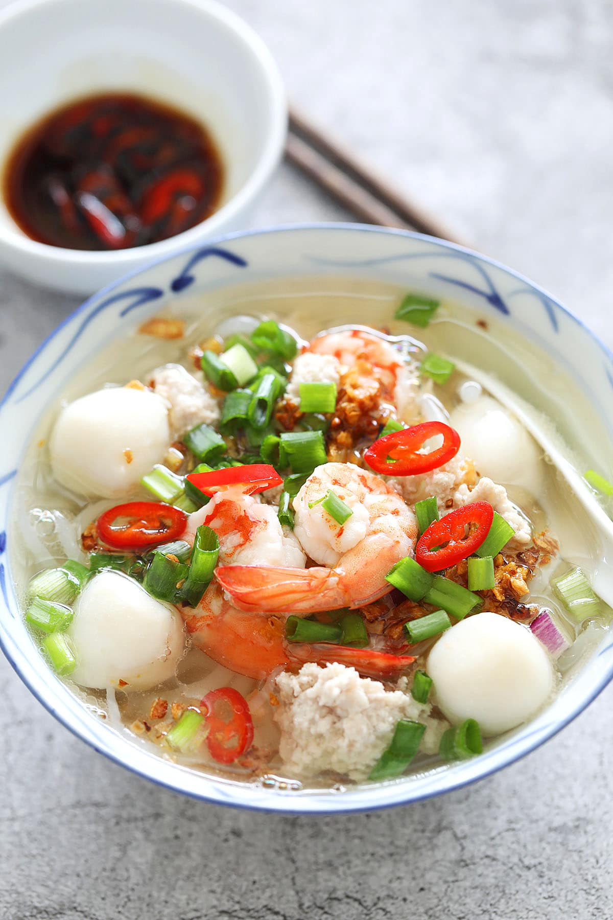 Soup with rice noodles served with a pair of chopsticks.