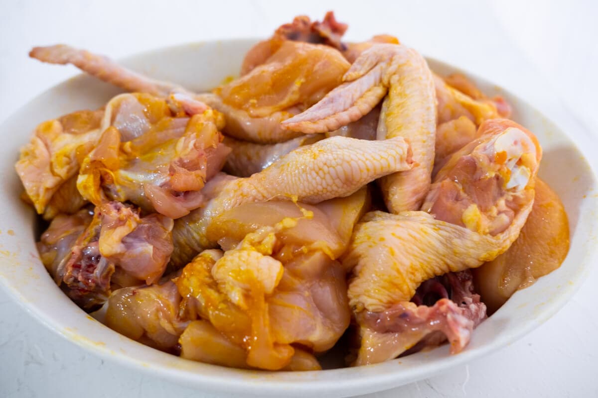 Chicken rubbed with turmeric and salt, on a plate.