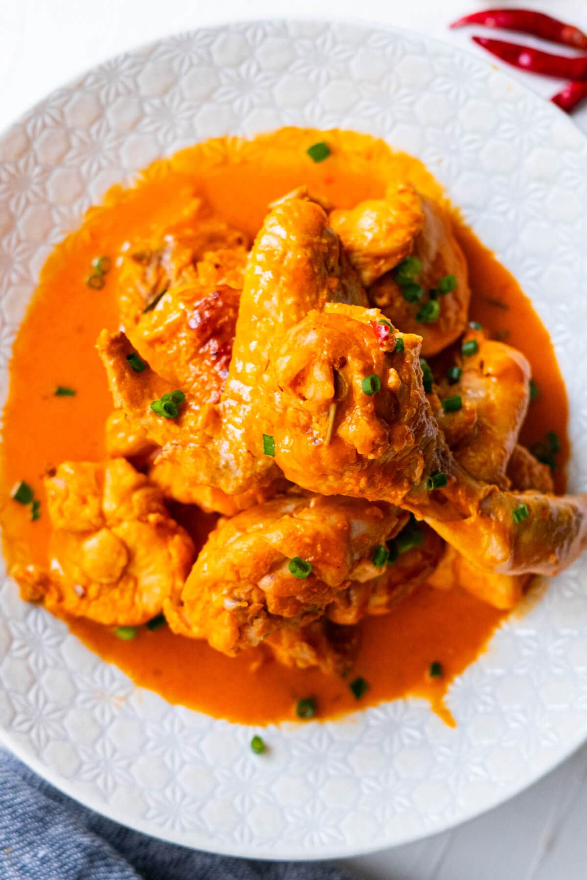 Ayam masak merah (chicken in spicy tomato sauce) served in a plate with red chilis on the side.