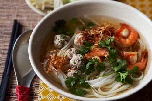 Homemade Phnom Penh noodle soup recipe with lime wedges and extra bean sprouts on the side, ready to serve.