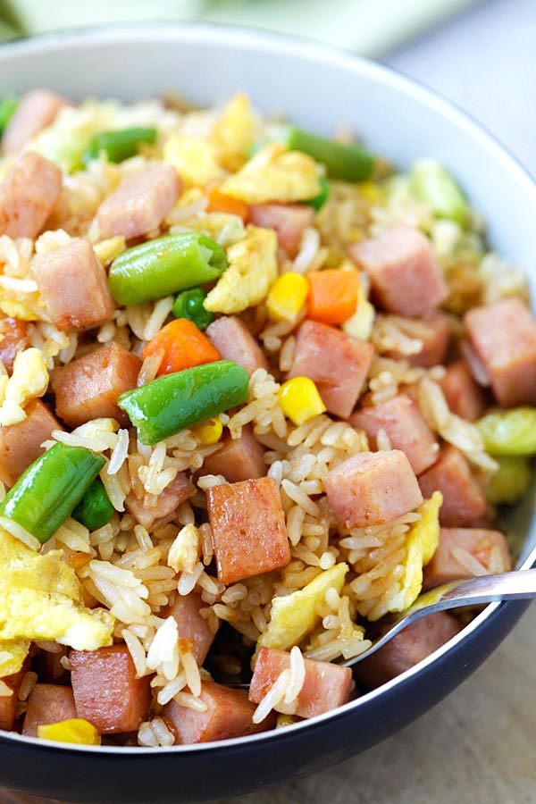 Fried rice with eggs, spam and mixed vegetables in bowl and a pair of chopsticks.