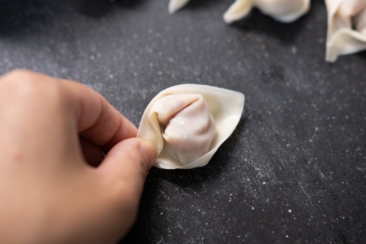 Pinch the corner of wonton wrapper to seal the wonton. 