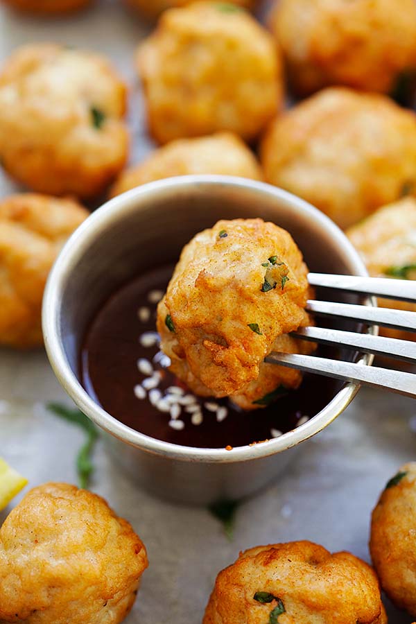 Chicken meatball recipe with ground chicken, lemon, garlic and lemon juice being dipped in sauce with a fork. 