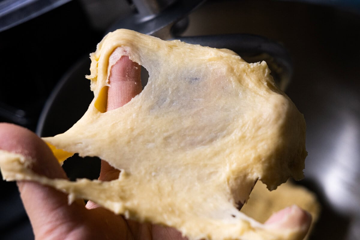 Stretchy bread dough on the hand.