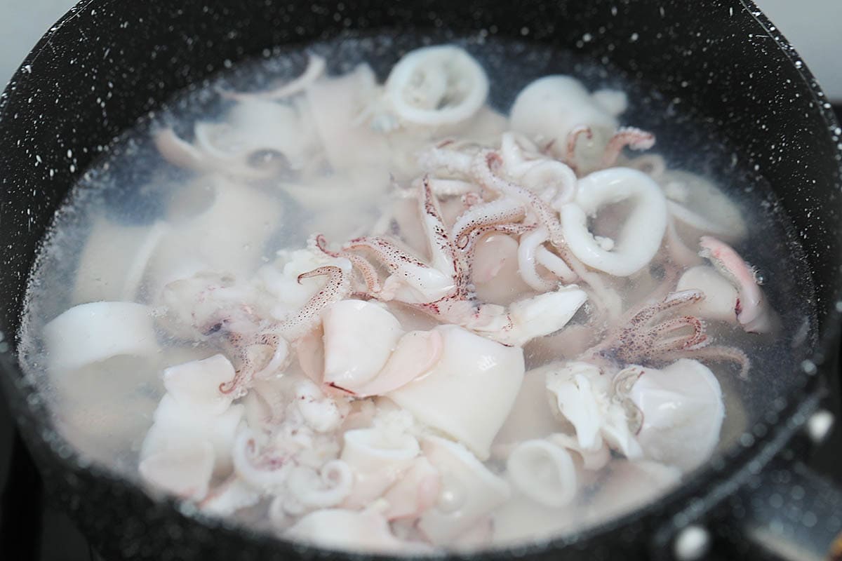 Blanching squid in hot boiling water. 