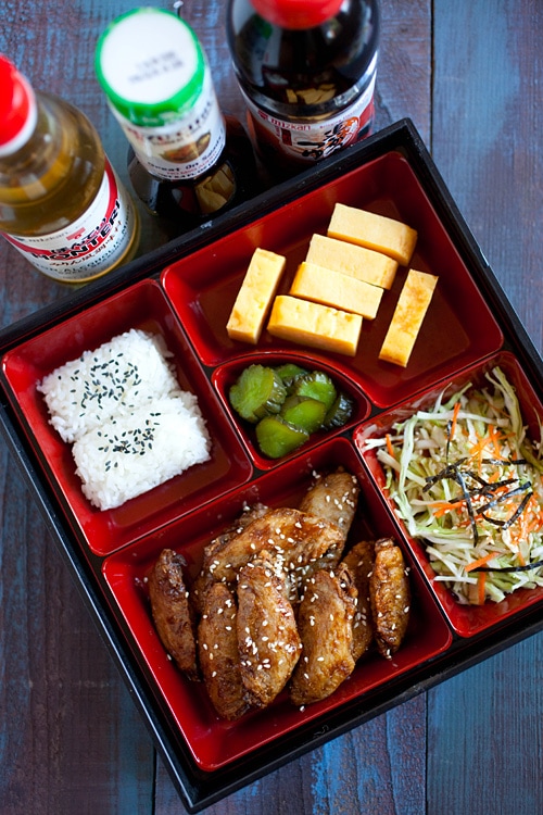 Easy Japanese-flavored chicken wings garnished with sesame seeds and served in a bento box.