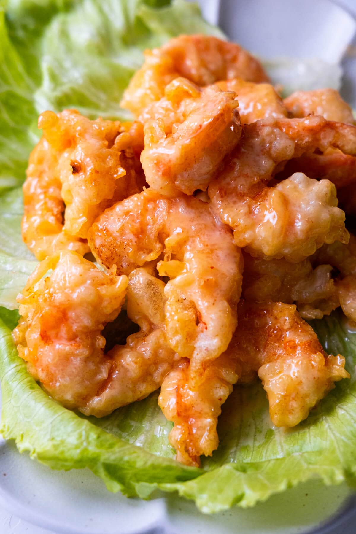 Dynamite shrimp on a piece of lettuce, served on a plate.