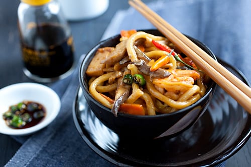 Quick and easy stir fried udon noodles in Asian brown thick sauce, served in a bowl with a pair of chopsticks.