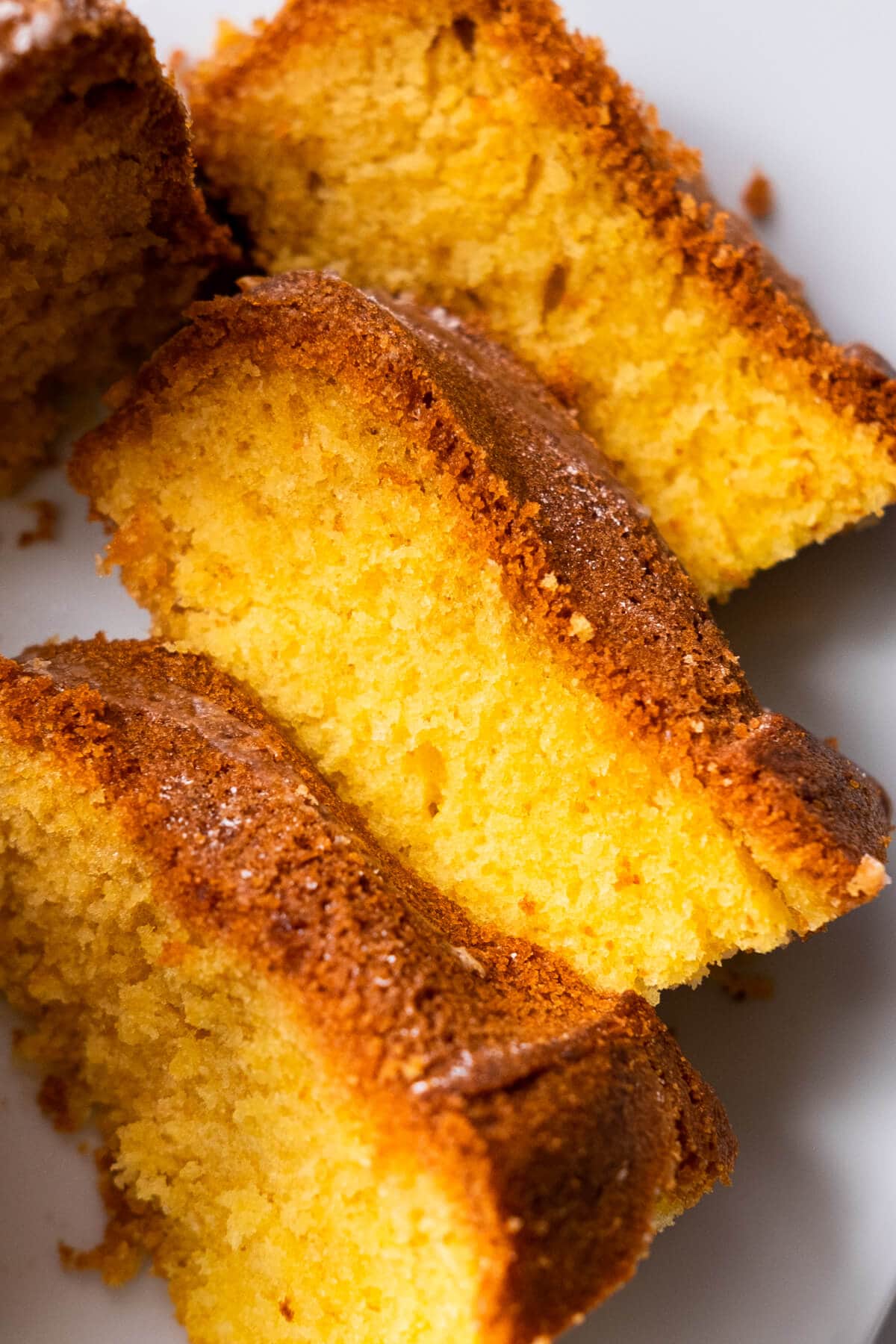 Slices of cake made with orange juice and orange zest served on a plate. 