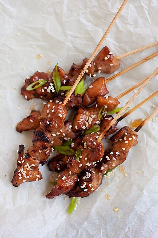 Top down view of Char grilled honey sesame chicken skewers on a sheet of baking paper.