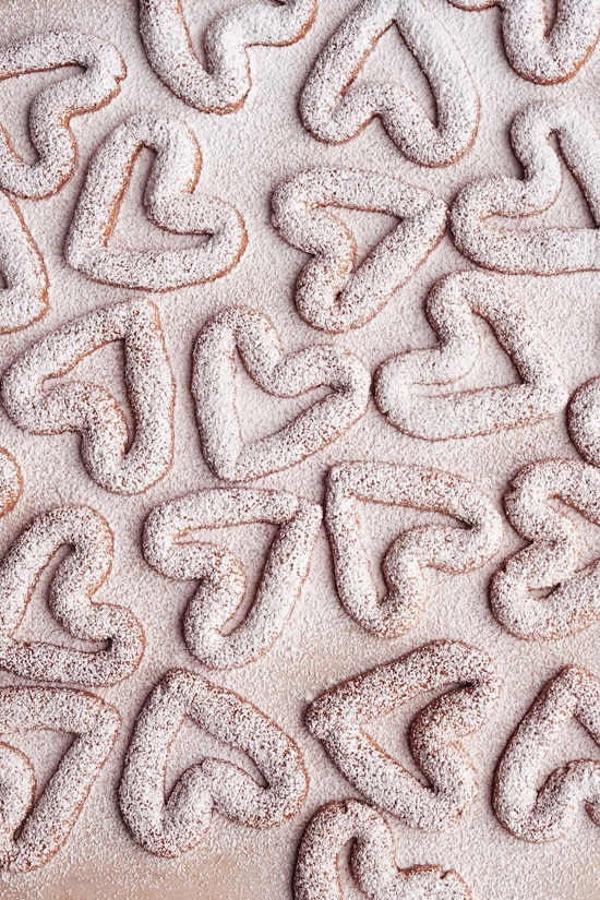 Heart shaped almond cookies coated with confectioners' sugar.