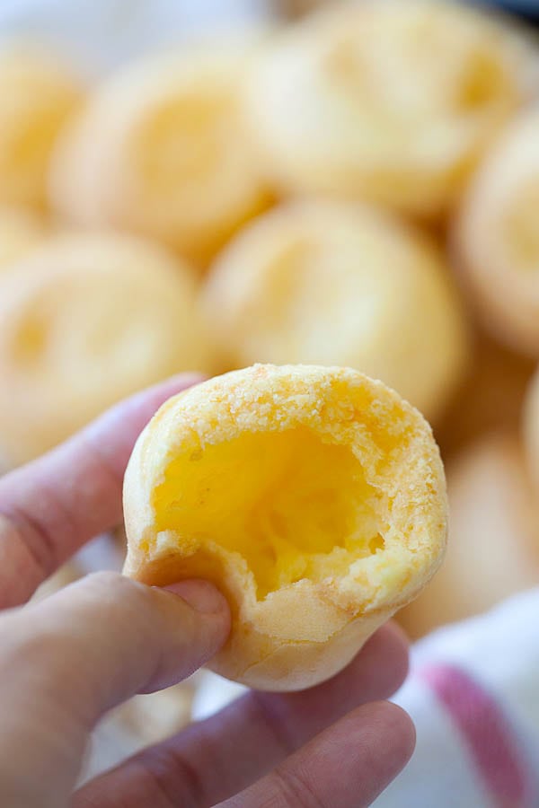 Puffy Brazilian cheese bread (Pão de Queijo) in hand ready to eat.