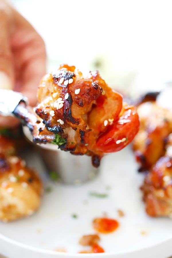 Bee holding Asian Baked Chicken Lollipop appetizer.