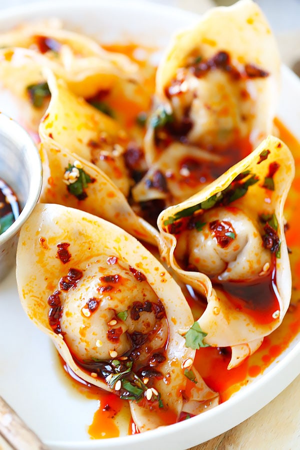 Homemade Szechuan spicy red oil dumplings and black vinegar sauce on a plate.