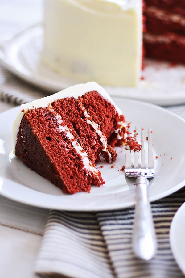 A piece of easy and delicious cake loaded with cream cheese frosting served in a plate with a fork.