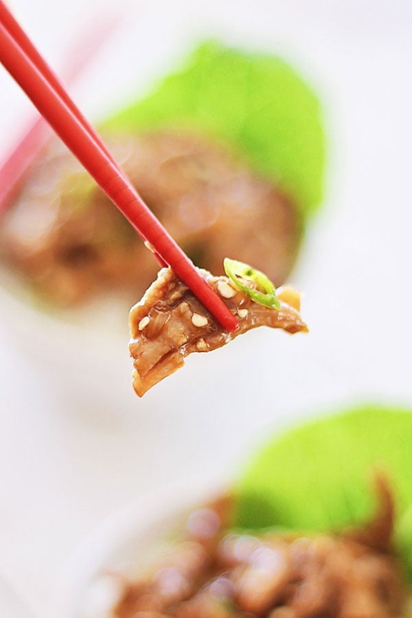 Crock Pot Honey Sesame Pulled Pork piece picked with a pair of chopsticks.