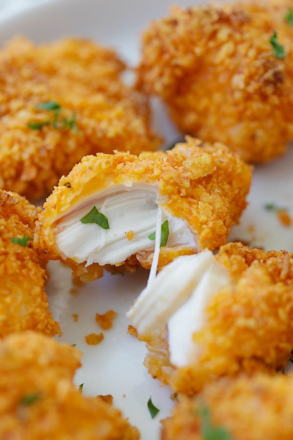 Close up tortilla chip-crusted chicken bites in half.