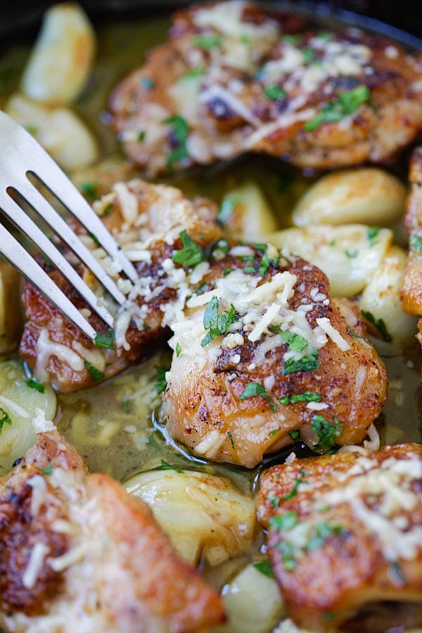 Skillet chicken with garlic and Parmesan cheese with a fork.