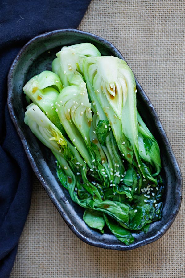 Easy roasted bok choy with light soy sesame dressing in serving dish.