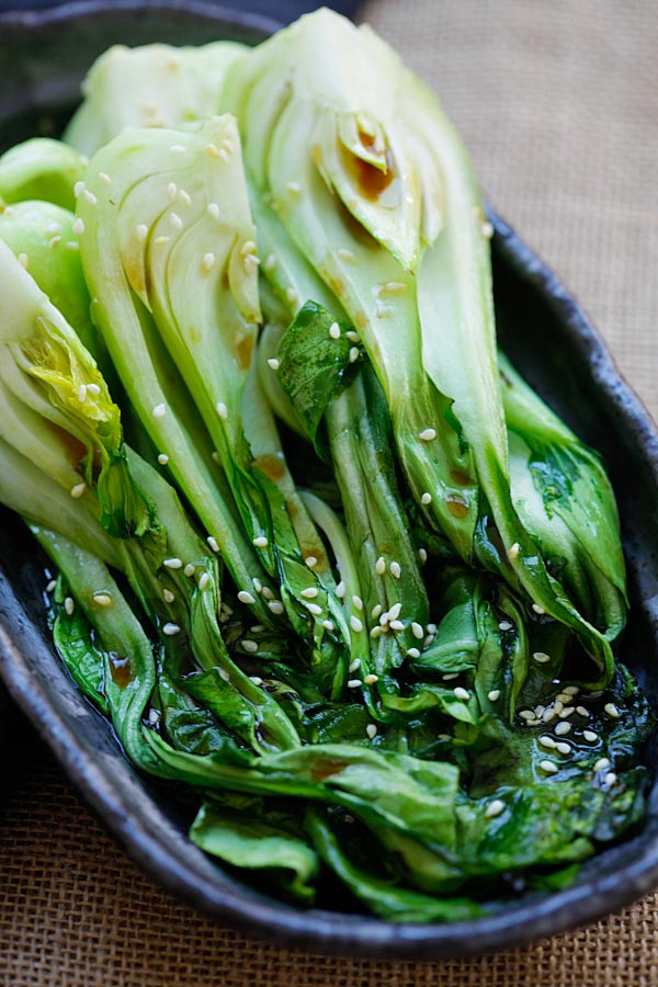 Roasted bok choy in serving dish with soy-sesame dressing, garnished with sesame seeds.