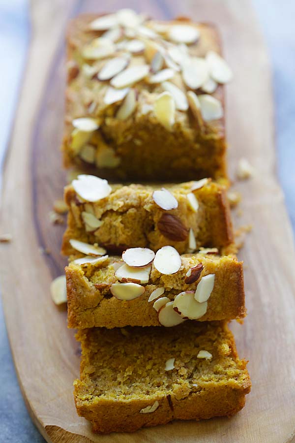 Sliced buttery almond pumpkin pound cake on a wooden chopping board.