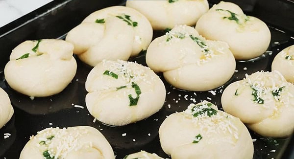 Dinner rolls topped with garlic herb butter and parmesan cheese.