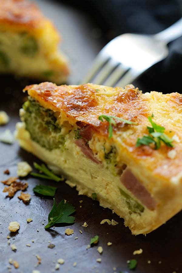 A slice of easy homemade French egg pie made with cheesy egg custard, ham and broccoli, ready to serve.