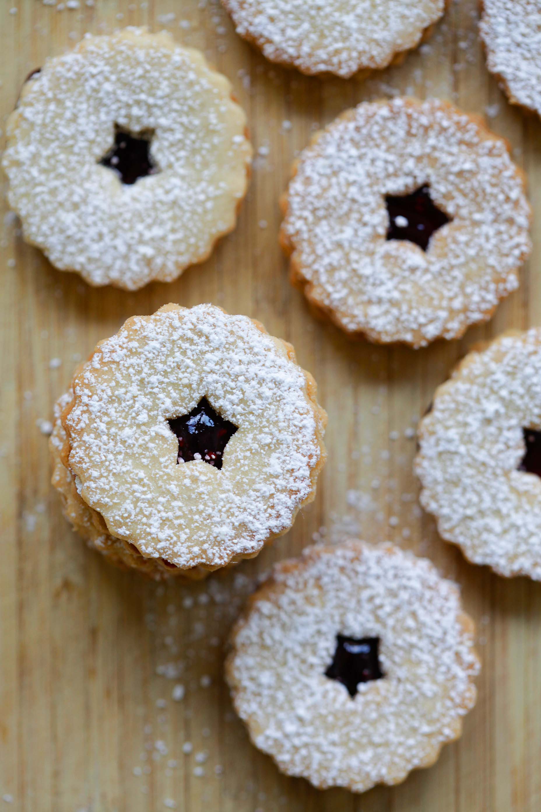 Easy baked mini buttery Linzer tarts with raspberry jam dusted with powdered sugar.