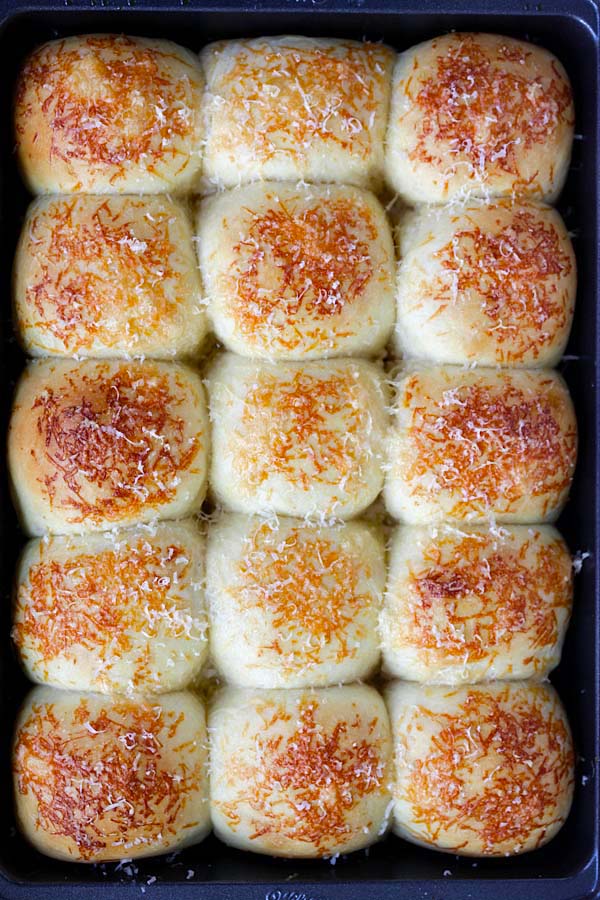 Delicious, easy and healthy homemade cheesy Parker House Rolls with Parmesan cheese in a baking tray.