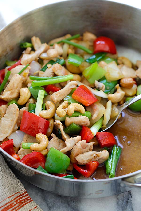 Thai stir-fry cashew nuts chicken with bell peppers, in brown Asian sauce in a skillet.