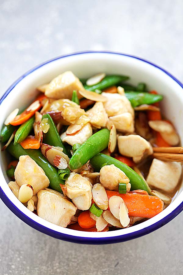 Easy and healthy chicken stir-fry with almonds, peas and carrots in Chinese brown sauce, served in a metal bowl.