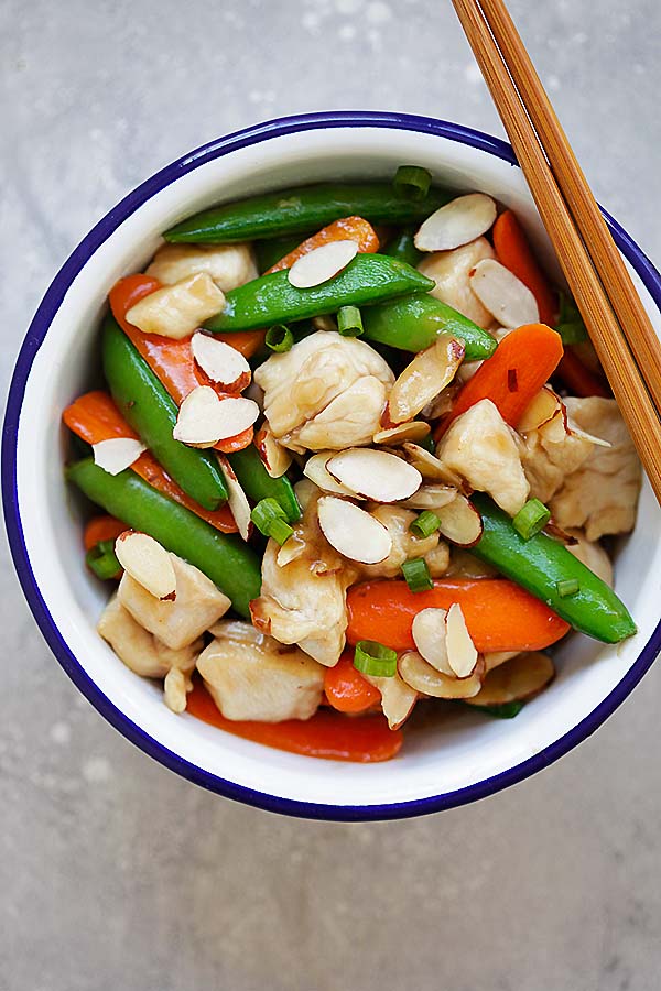 Stir fry Almond nuts with chicken breasts in Chinese brown sauce, in a metal bowl.