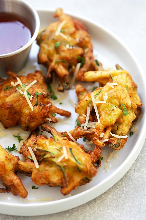 Close up crispy deep fried zucchini fritters poked with a fork.