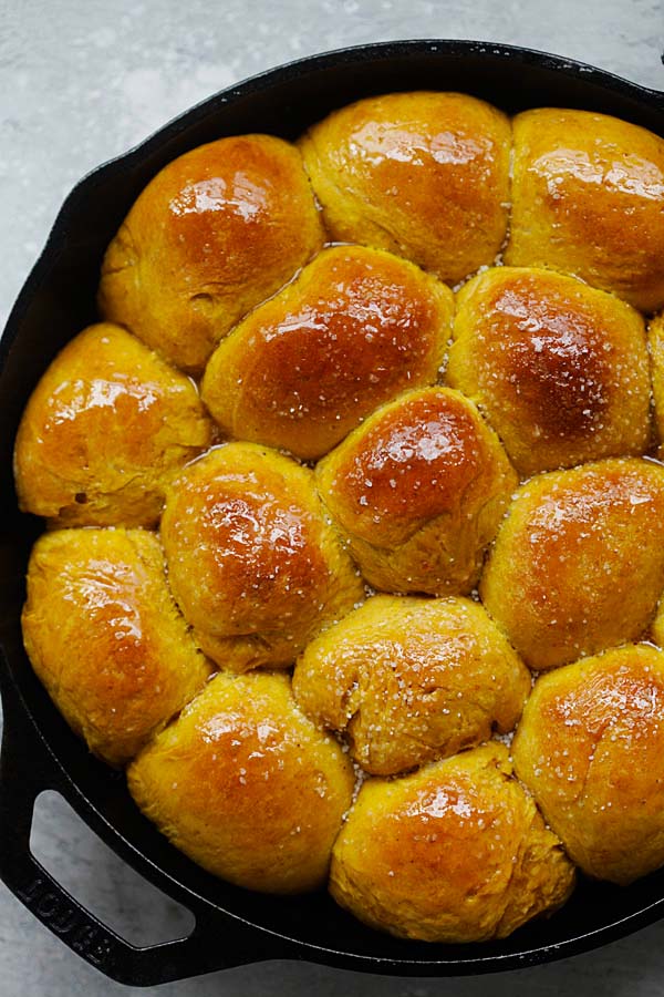 Golden pumpkin dinner rolls in a skillet.