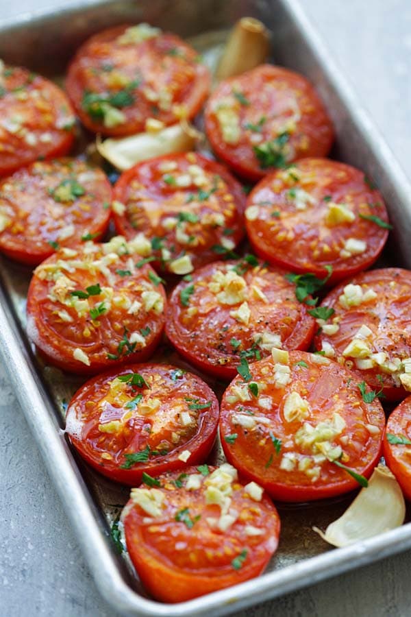 Juicy slow oven Roasted Tomatoes with garlic sauce in a baking tray.