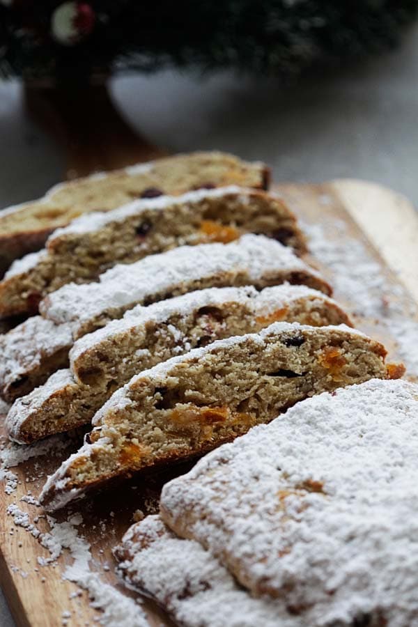 Easy and quick delicious homemade holiday bread recipe loaded with pecans and dried fruits, sliced and placed on a wooden chopping board.