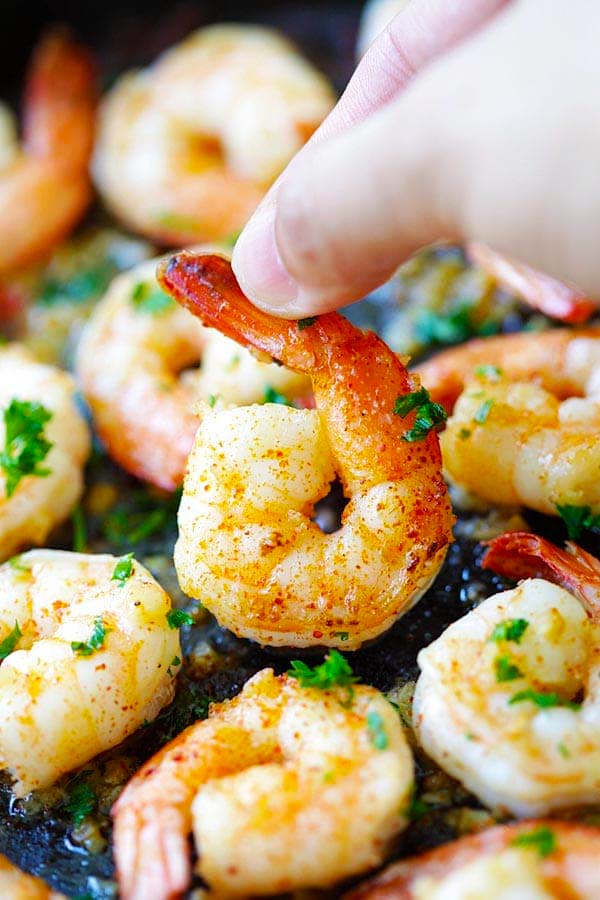 Picking up garlic shrimp with fingers in this shrimp recipe.