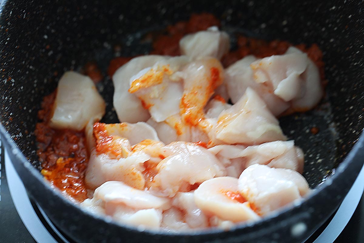 Cooking chicken with red curry paste. 