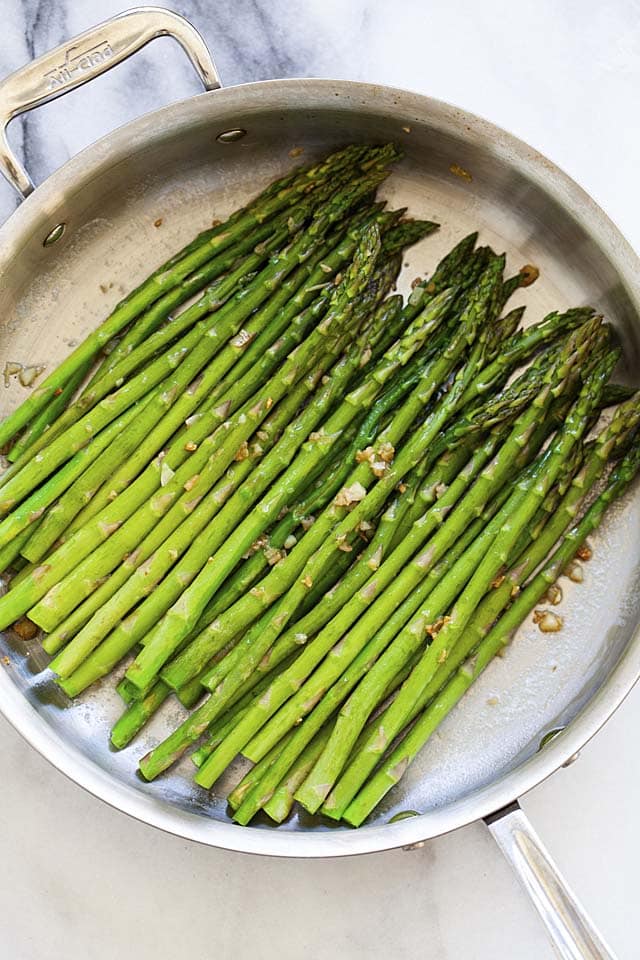 Sauteed asparagus with garlic, butter and lemon in a skillet.