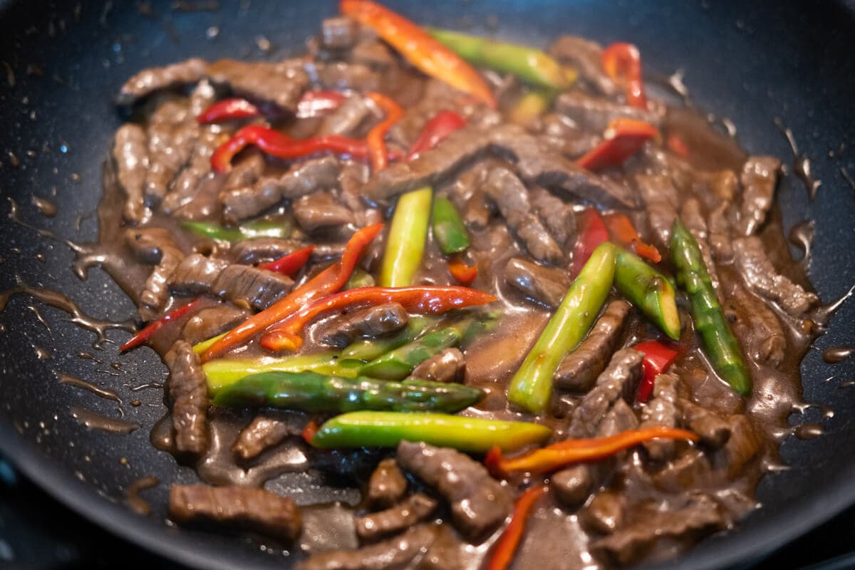 Add sauce and bell pepper to the wok, and stir well with beef and asparagus. 