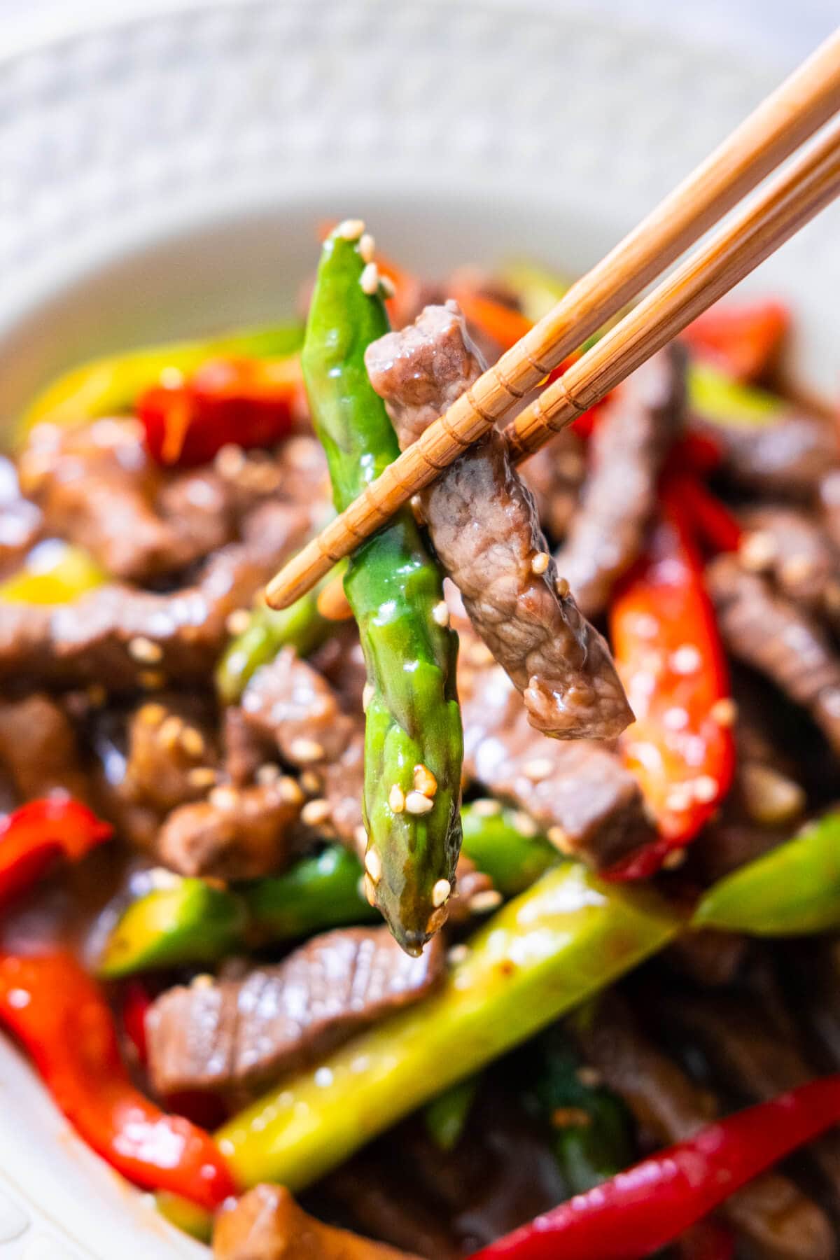 Beef and asparagus grabbed with a pair of chopsticks.